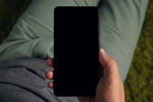 iPhone med sort skærm holdt i hånden før genstart