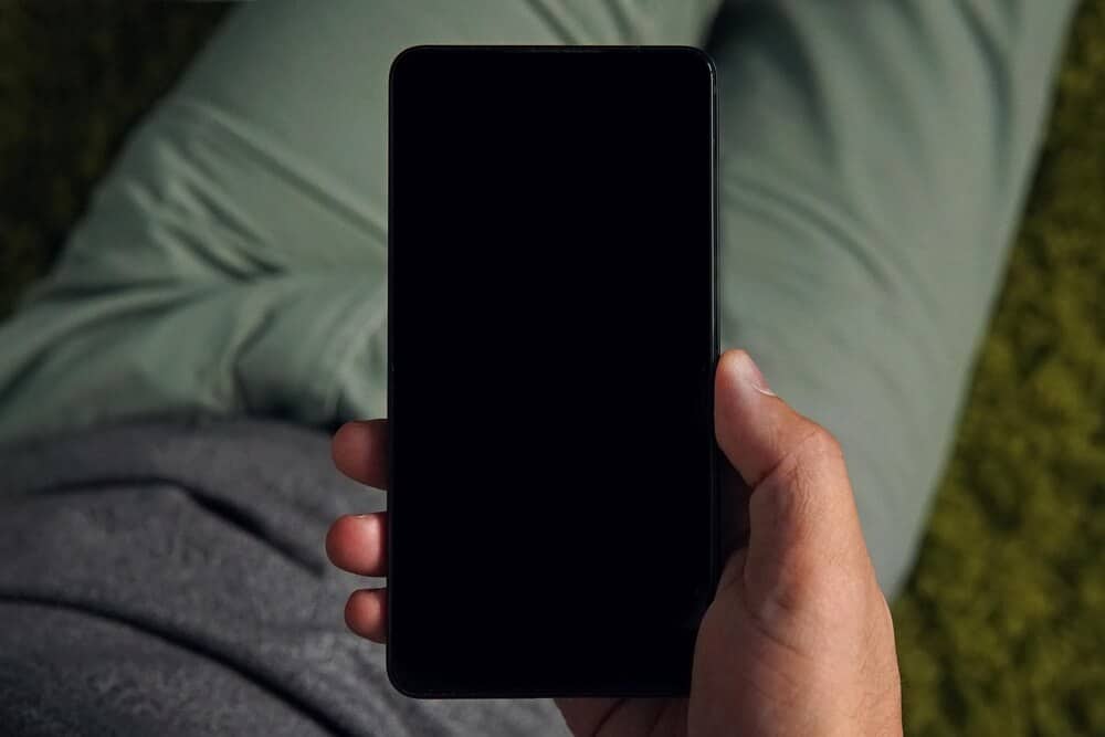 iPhone med sort skærm holdt i hånden før genstart